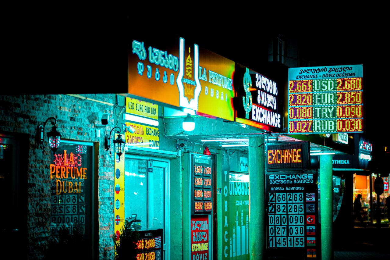 services-04 Night view of a brightly lit storefront and currency exchange signs in Batumi, Georgia.